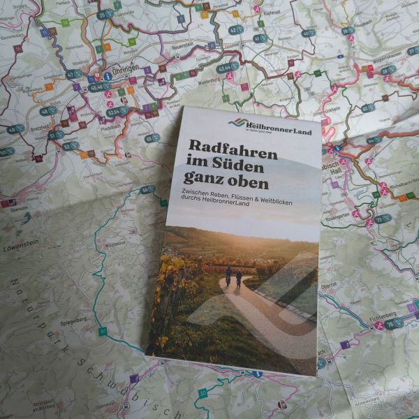 Colorful regional biking map with routes and icons, plus a brochure titled 'Radfahren im Süden ganz oben' resting on it.